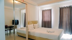 Una habitación de hotel con una cama, un escritorio, un televisor y un ventanal corredera.