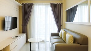 A modern living room with a flat-screen TV, a sofa, a small table, and a window with curtains.