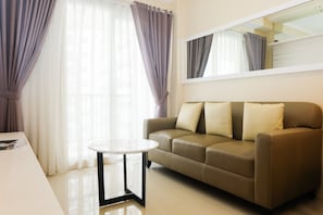 A modern living room with a beige sofa, a small round table, and sheer curtains.