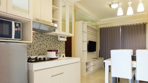 A modern kitchen with a microwave, stove, and white cabinets. There is a dining area with a table and chairs.