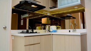 A modern kitchen with a built-in microwave, a coffee maker, and a kettle on the counter. - Brand New And Modern 1Br Signature Park Grande Apartment (Jakarta)