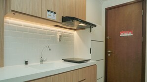 Une cuisine moderne avec un plan de travail blanc, des armoires en bois, une hotte en acier inoxydable et une porte dotée d’un code QR.