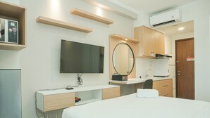 Une chambre d’hôtel moderne équipée d’un lit, d’une télévision, d’un miroir, d’un bureau et d’une kitchenette.