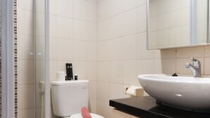 Un baño con inodoro, lavamanos y zona de ducha.