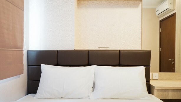Una cama bien hecha con sábanas blancas y un cabecero oscuro.