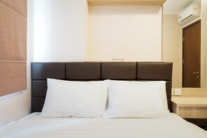 A neatly made bed with white linens and a dark headboard.