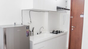Een kleine keuken met een koelkast, gootsteen, fornuis en kastjes.