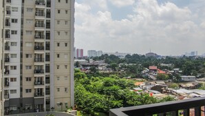 Een hoog appartementencomplex met meerdere balkons en uitzicht op een stadsgezicht met diverse gebouwen en groen.