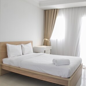 Ein ordentlich bezogenes Bett mit weißen Leinen und einem Holz-Kopfteil in einem modernen Hotelzimmer.