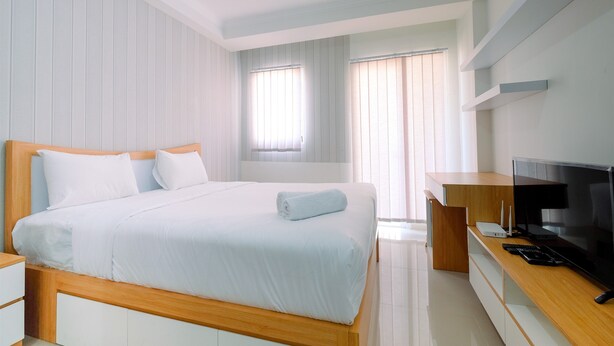 Een moderne hotelkamer met een groot bed, een houten bureau, een flatscreen televisie en een raam met zonwering.