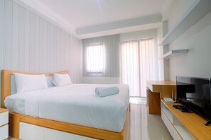 Ein modernes Hotelzimmer mit einem großen Bett, einem Holztisch, einem Flachbildfernseher und einem Fenster mit Jalousien.