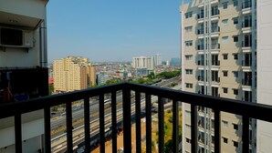 Een hoog gebouw met meerdere balkons, een uitzicht op een drukke weg en omliggende gebouwen.