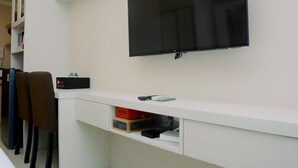 Ein modernes Zimmer mit einem an der Wand befestigten Fernseher, einem weißen Konsolentisch und einem Sessel.