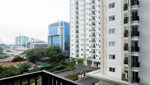A high-rise residential building with multiple balconies, a modern glass building, and a well-maintained garden area.