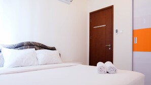 A neatly made bed with white linens and a rolled towel on the side.