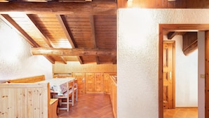 Un interior de madera con cocina, comedor y una puerta que da a otra habitación.