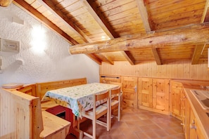 Um interior em madeira com um banco, mesa e armários.