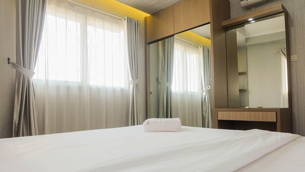 A hotel room with a bed, a bathroom mirror, and curtains. - Comfy 2Bedroom At Signature Park Grande Apartment (Jakarta)