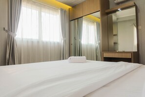 A hotel room with a bed, a bathroom mirror, and curtains. - Comfy 2Bedroom At Signature Park Grande Apartment (Jakarta)
