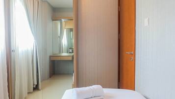 A hotel room with a bed, a wooden door, and a bathroom visible through an open door.