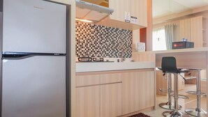 A modern kitchen with a refrigerator, a tiled backsplash, and bar stools. - Comfy 2Bedroom At Signature Park Grande Apartment (Jakarta)