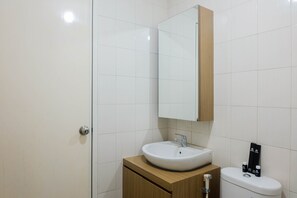 A bathroom with a white sink, a mirror, and a toilet. - Comfy 2Bedroom At Signature Park Grande Apartment (Jakarta)