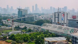 A cityscape with a prominent bridge, high-rise buildings, and a construction site. - Warm And Cozy 2Br Signature Park Grande Apartment (Jakarta)