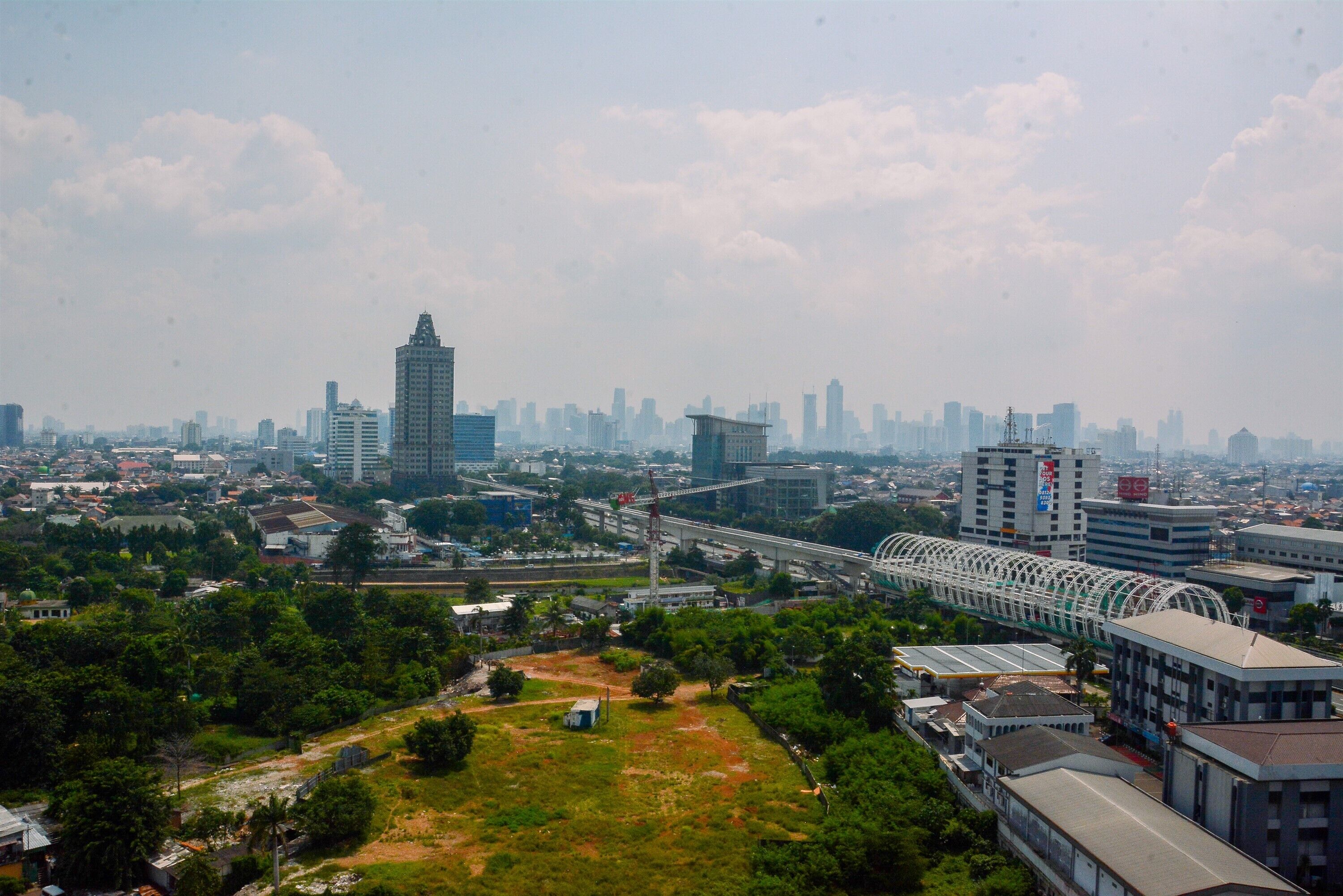 A cityscape with a prominent bridge, high-rise buildings, and a mix of greenery.