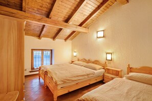 A bedroom with two wooden beds, a wooden nightstand, a window with curtains, and a wooden ceiling. - Apartment 'Chalet Meridiana Appartamento 10' with Mountain View (Livigno)