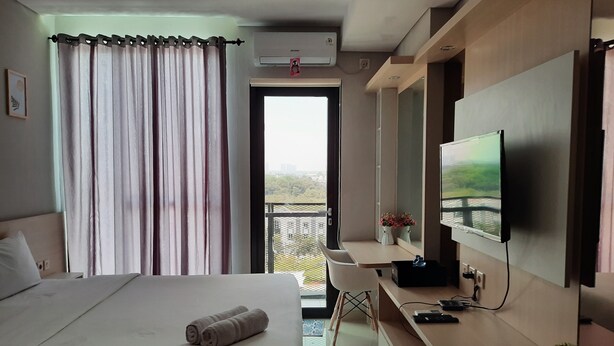 Quarto de hotel com cama, escrivaninha, televisão e varanda com vista.