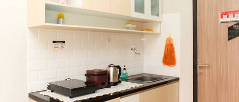 A kitchen with a countertop, a kettle, a coffee maker, and a sink.