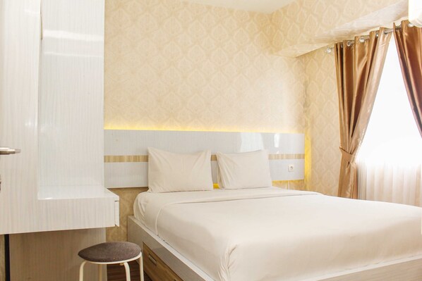 A hotel room with a bed, a nightstand, a lamp, and a window with curtains.