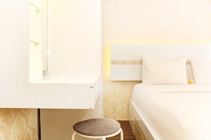 A hotel room with a bed, a small stool, a mirror, and a wall-mounted shelf.