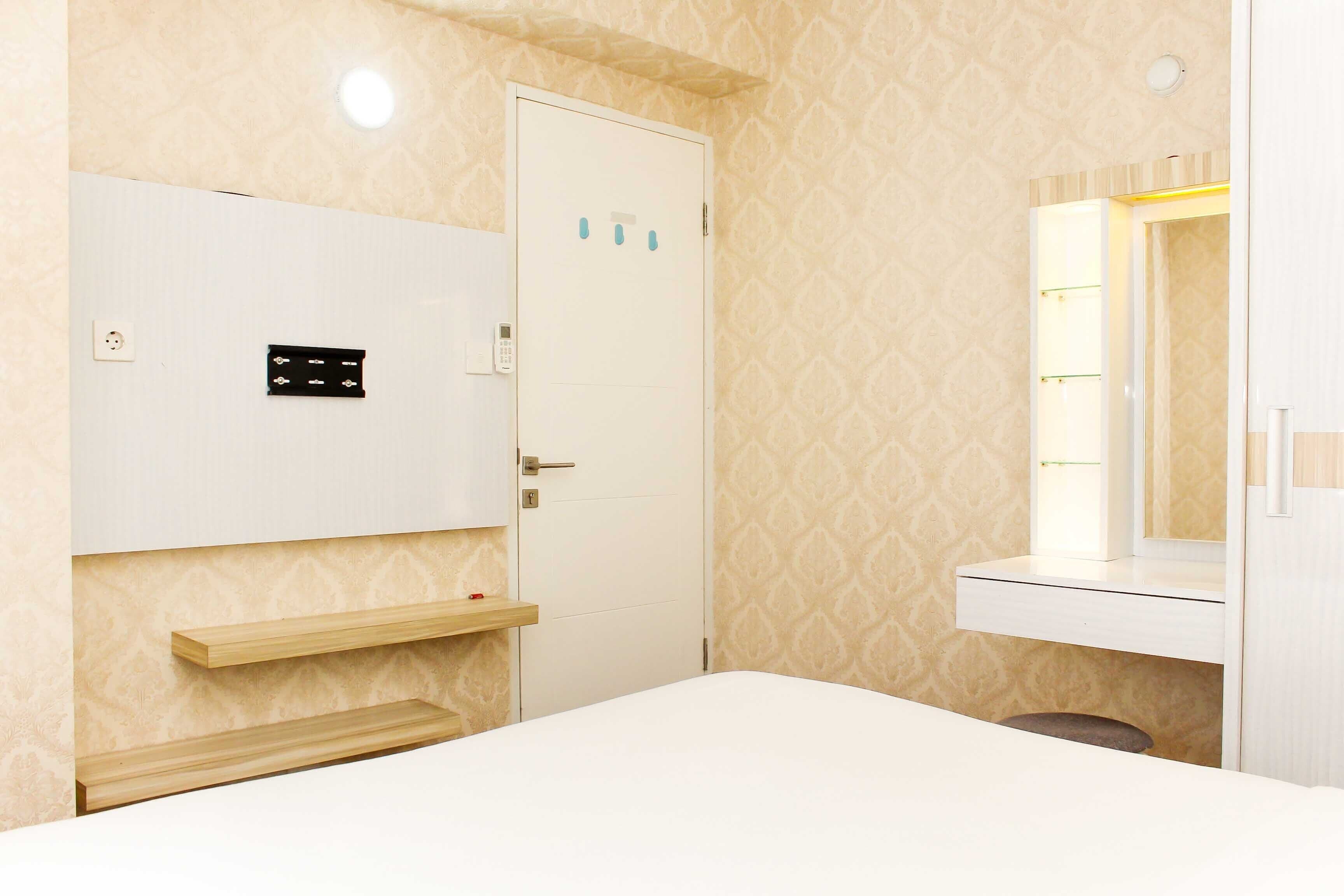A hotel room with a bed, a wardrobe, a mirror, and a shelf.