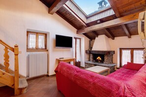 Ein gemütliches Wohnzimmer mit Kamin, Fernseher und einer Holztreppe.