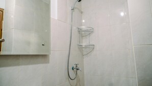 A bathroom with white tiles, a shower with a handheld showerhead, and a metal shelf. - Stunning And Comfy Studio Amazana Serpong Apartment (South Tangerang)