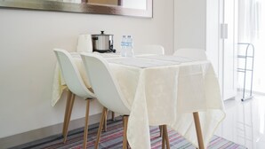 A hotel room with a dining table set for two, a kettle, and two water bottles. - Cozy And Spacious 1Br Apartment At Parkland Avenue (South Tangerang)