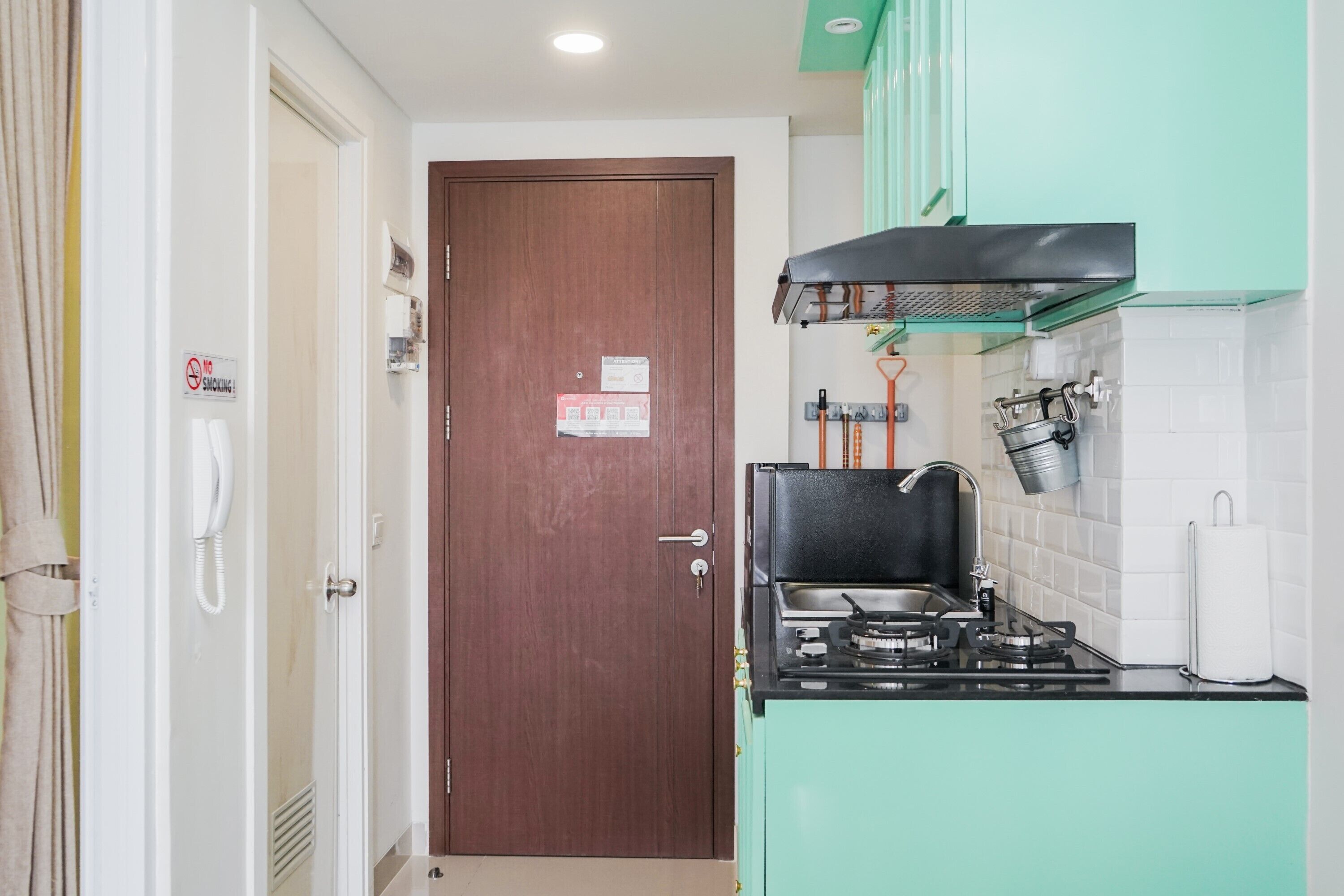 A compact kitchen with a stove, sink, and green cabinets.