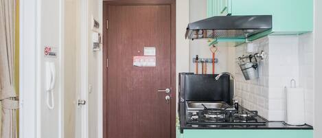 A compact kitchen with a stove, sink, and green cabinets.