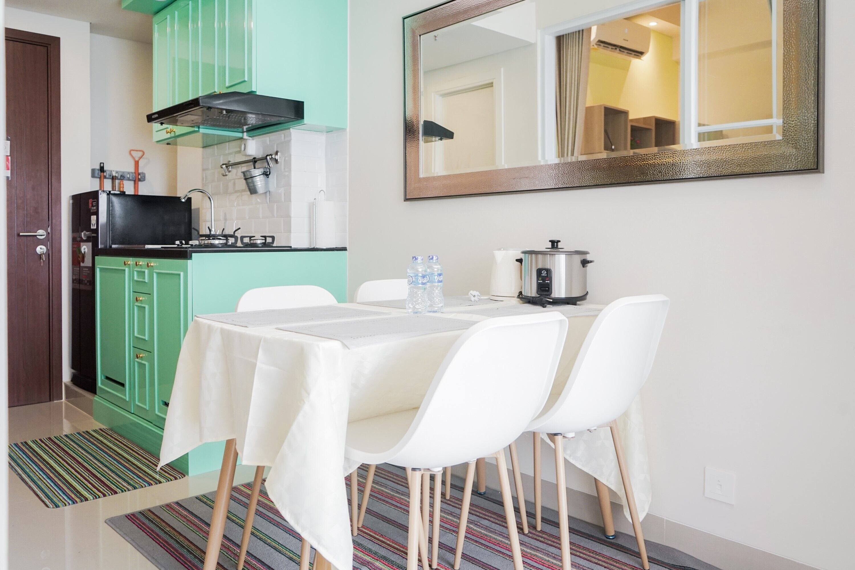 Una cocina compacta con una mesa preparada para cuatro personas, un microondas y un dispensador de agua.