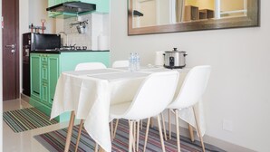 A compact kitchen with a table set for four, a microwave, and a water dispenser. - Cozy And Spacious 1Br Apartment At Parkland Avenue (South Tangerang)