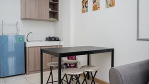 Una cocina compacta con una mesa, taburetes, un refrigerador y un microondas.
