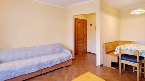 A room with a sofa, a table with a chair, a wooden door, and a light fixture. - Apartment 'Chalet Meridiana 8' with Mountain View (Livigno)