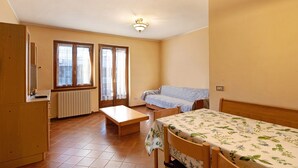 A small, well-lit room with a bed, a table, a bench, and a radiator. - Apartment 'Chalet Meridiana 8' with Mountain View (Livigno)