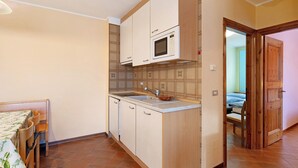 A compact kitchen with a microwave, sink, and wooden cabinets. - Apartment 'Chalet Meridiana 8' with Mountain View (Livigno)