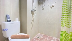 A bathroom with a toilet, shower, and a green polka dot shower curtain. - Modern Studio Room At Taman Melati Jatinangor Apartment (Hegarmanah)