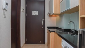 A compact kitchen with a built-in oven, a microwave, and a sink. - Comfortable And Warm Studio Room At Menteng Park Apartment (Jakarta)