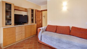 Une petite pièce comprenant un lit, des armoires en bois, un téléviseur et une porte.