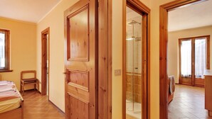 Une pièce comprenant un lit, une chaise, une porte en bois et un espace douche.