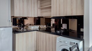 Une cuisine compacte avec des meubles en bois, un lave-linge encastré et une cuisinière noire.
